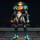 Samus Aran stands facing the viewer in a dimly lit sci-fi facility of some kind.